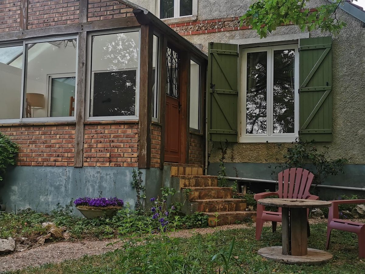 La maison de L'Escale 207 : véranda vitrée, volets verts et jardin